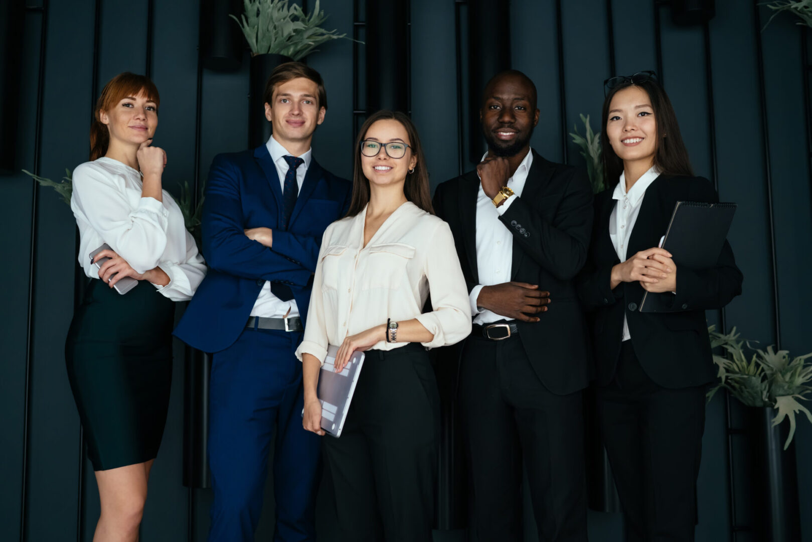 Half length portrait of successful male and female leaders in formal clothing enjoying together workflow, happy multicultural lawyers smiling at camera during brainstorming meeting for collaborate
