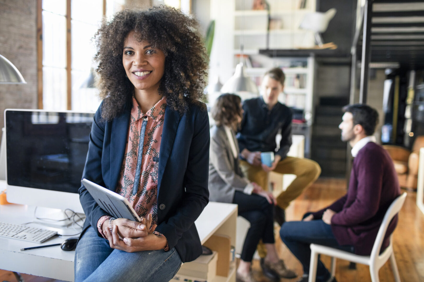 Portrait of a young entrepreneur women in the office, colleagues are in the background talking.