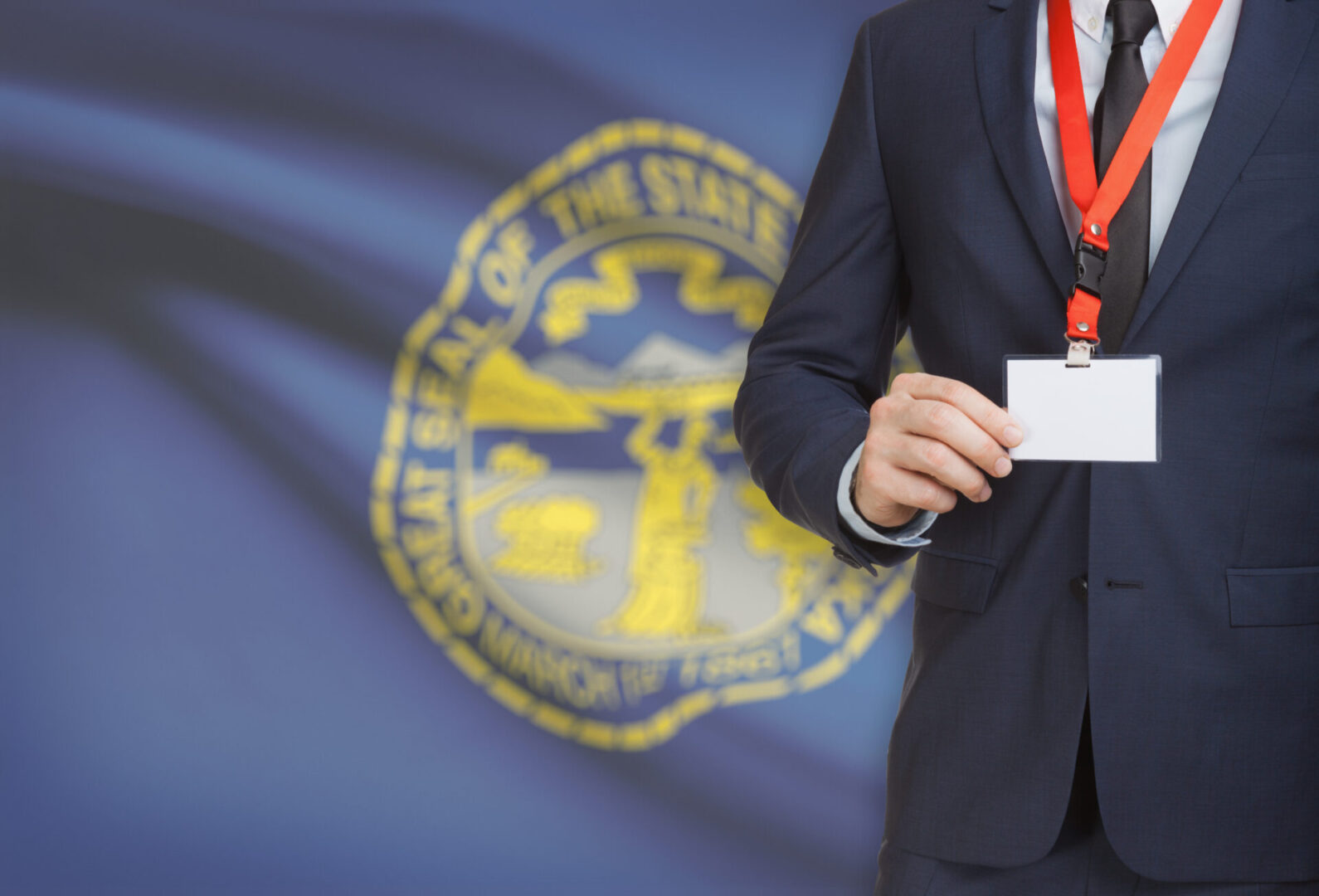 Businessman holding name card badge on a lanyard with US state flag on background - Nebraska