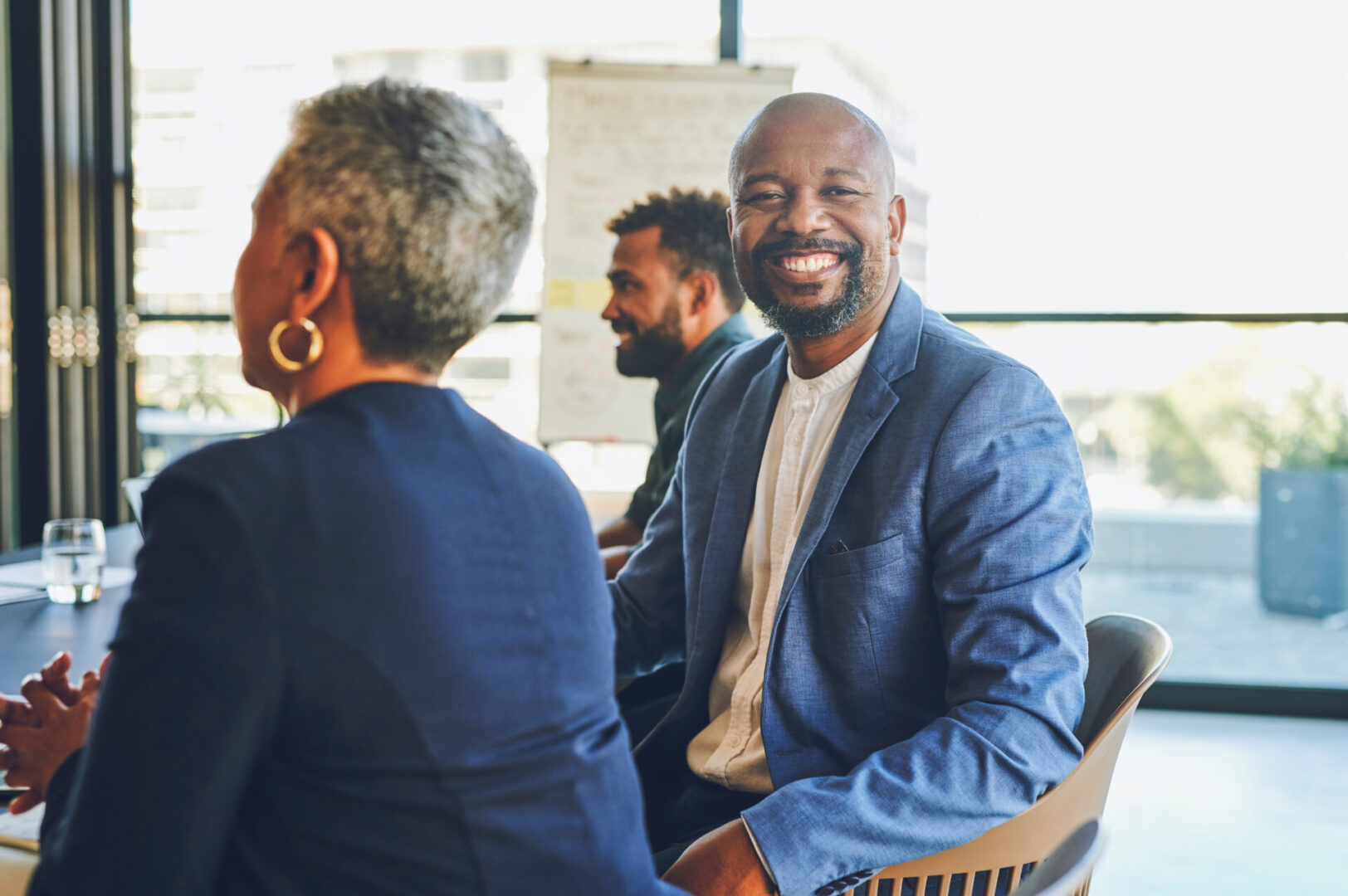 Man leader, manager or CEO in a meeting with a team in the room to talk about the vision and mission for company growth or development. Portrait of a happy employee or boss in a workshop for planning